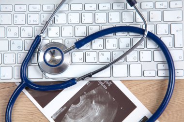 Beyaz ahşap bir masa üstünde a laptop yanında sağlık stetoskop