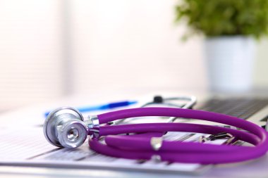 Beyaz ahşap bir masa üstünde a laptop yanında sağlık stetoskop