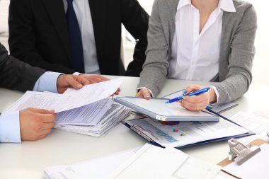 İş adamları el sıkışır, masada otururlar.