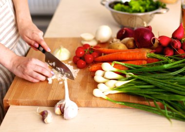 Mutfakta sebze doğrayan genç bir kadın.