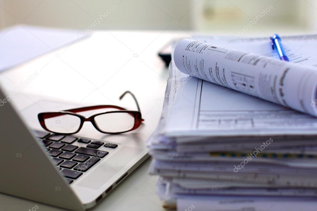 Stack of papers and glasses lying on table desaturated