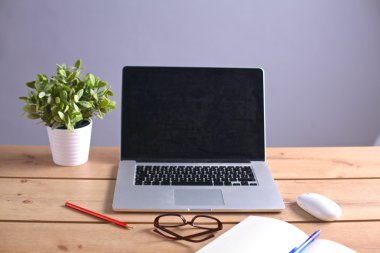 Laptop ahşap bir masada duruyor.