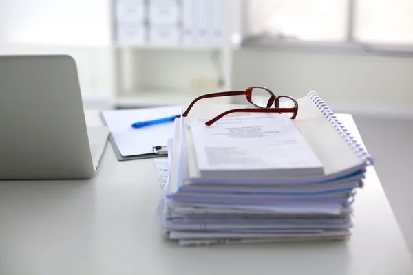 Laptop with stack of folders on table on white background — Stock Photo, Image