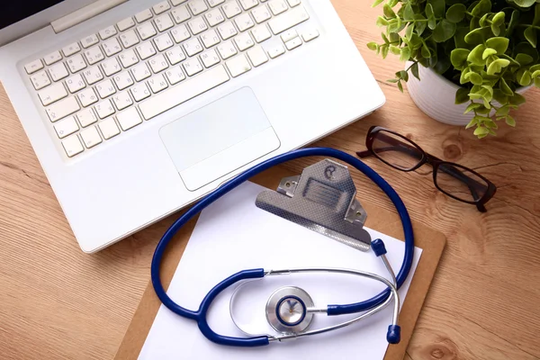 A medical stethoscope near a laptop on a wooden table, on white — Stock Photo, Image