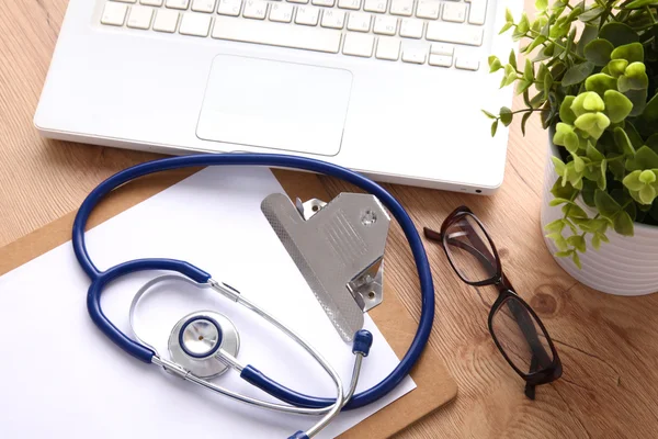 A medical stethoscope near a laptop on a wooden table, on white — Stock Photo, Image
