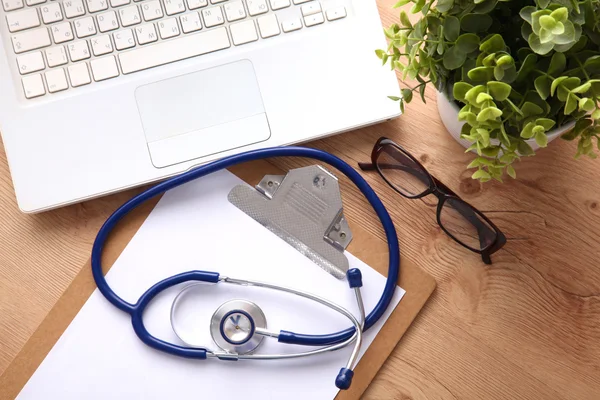 A medical stethoscope near a laptop on a wooden table, on white — Stock Photo, Image