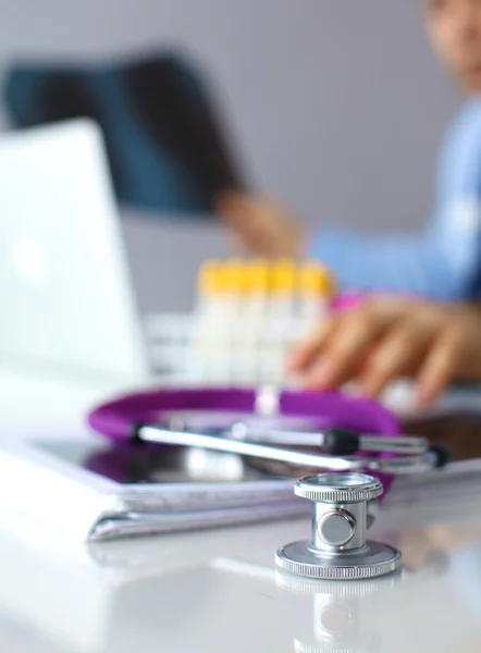 Um estetoscópio médico perto de um laptop em uma mesa de madeira, em branco — Fotografia de Stock