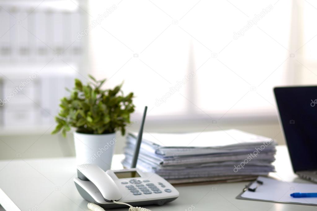 Laptop with stack of folders on table on white background