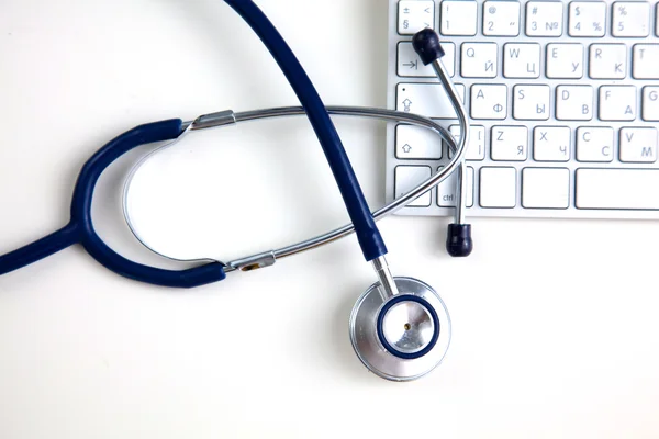 Un estetoscopio médico cerca de un portátil en una mesa de madera, en blanco — Foto de Stock