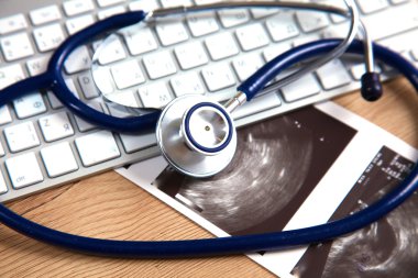 Beyaz ahşap bir masa üstünde a laptop yanında sağlık stetoskop