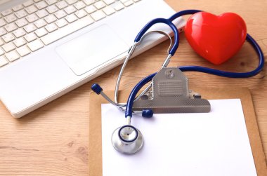 Beyaz ahşap bir masa üstünde a laptop yanında sağlık stetoskop