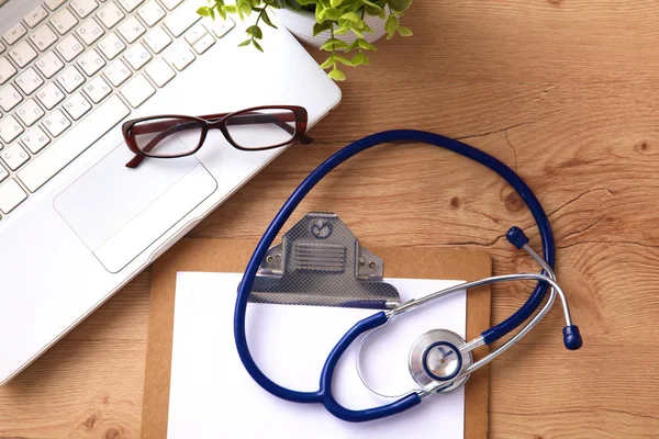 A medical stethoscope near a laptop on a wooden table, on white — Stock Photo, Image