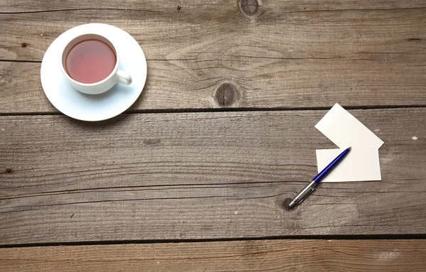 Blank business cards with pen and tea cup on wooden office table