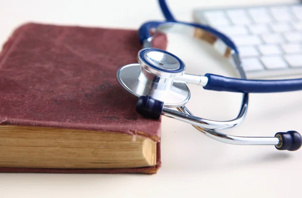 Medical stethoscope with old books and laptop on a table — Stock Photo, Image