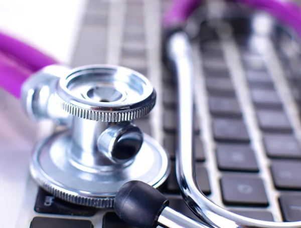 Uno stetoscopio medico vicino a un computer portatile su un tavolo di legno, su bianco — Foto Stock