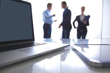 Masanın üstünde laptop odaklanmak. Arka plan üzerinde bulanık insanlar
