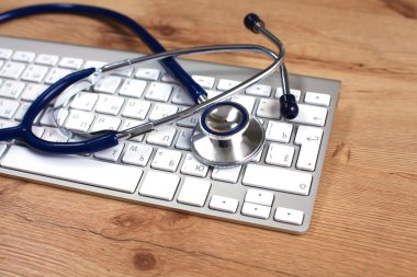 Beyaz ahşap bir masa üstünde a laptop yanında sağlık stetoskop