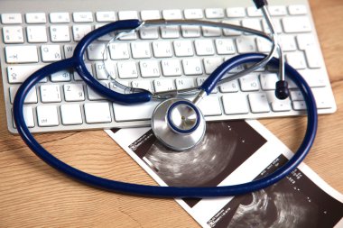 Beyaz ahşap bir masa üstünde a laptop yanında sağlık stetoskop