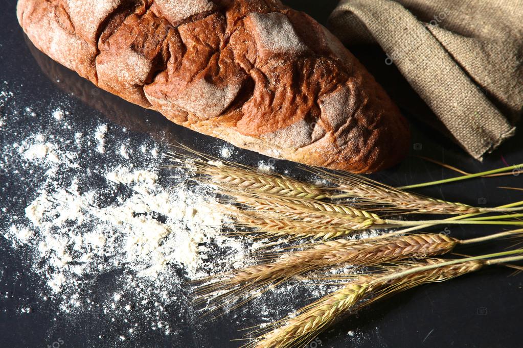 Pain croûté rustique et épis de blé sur une table en bois sombre image