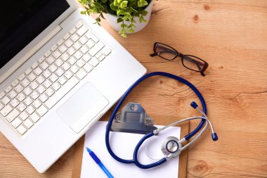 Beyaz ahşap bir masa üstünde a laptop yanında sağlık stetoskop
