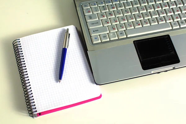 Mesa de escritório com bloco de notas em branco e laptop — Fotografia de Stock