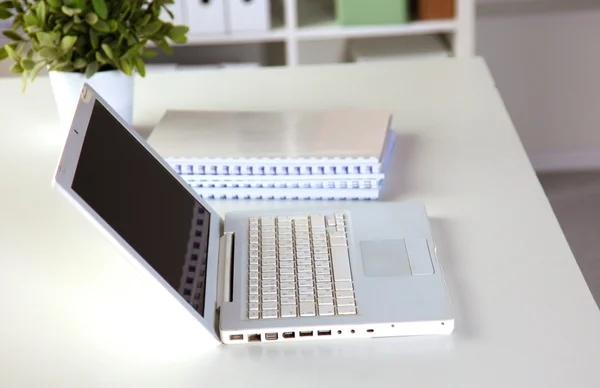 Mesa de oficina con bloc de notas en blanco y portátil — Foto de Stock