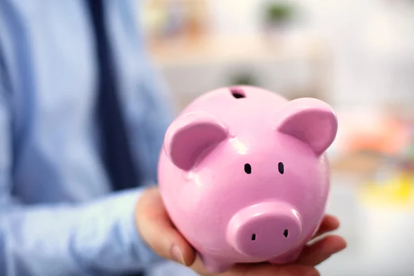 Affärsman holding piggy box, står i office — Stockfoto