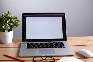 Laptop ahşap bir masada duruyor.