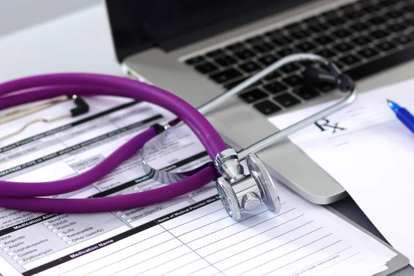 Um estetoscópio médico perto de um laptop em uma mesa de madeira, em branco — Fotografia de Stock