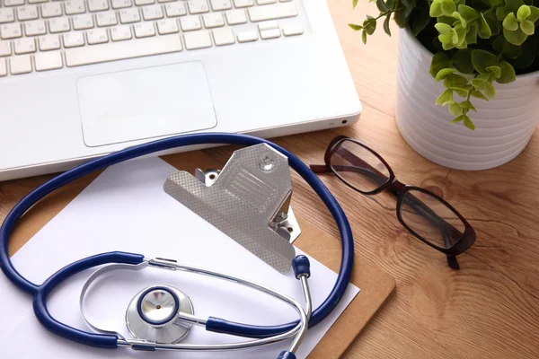 A medical stethoscope near a laptop on a wooden table, on white — Stock Photo, Image