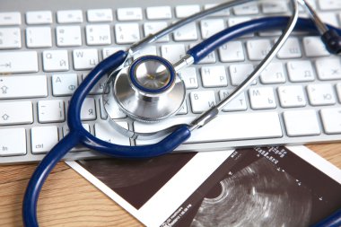 Beyaz ahşap bir masa üstünde a laptop yanında sağlık stetoskop