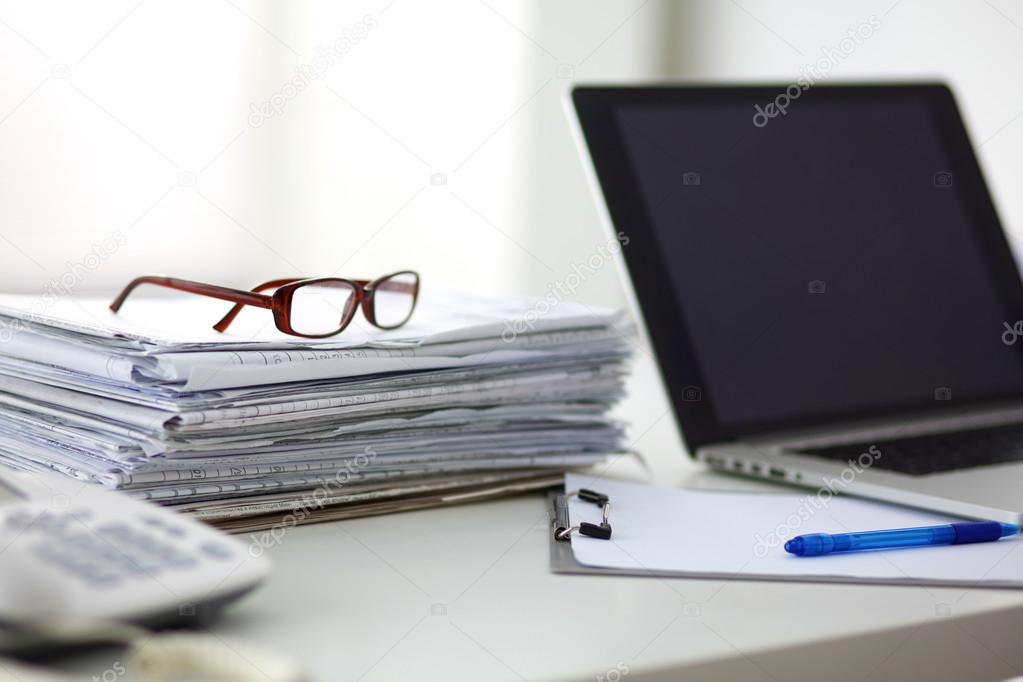 newspaper,eyeglasses, cup and laptop