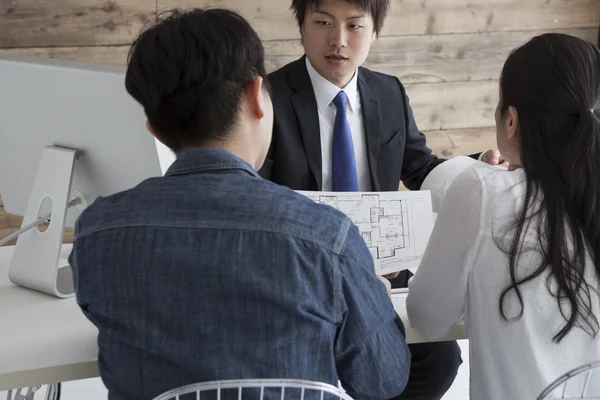 Pareja en agencia inmobiliaria hablando con planificador de construcción — Foto de Stock