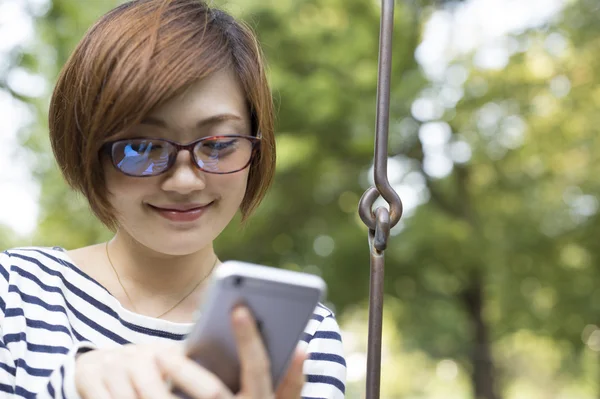 Wanita santai di taman dan menggunakan smartphone — Stok Foto