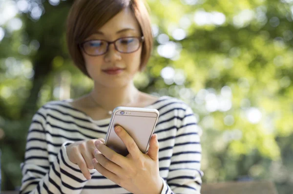 Juventud y tecnología. Mujer joven usando smartphone en parque verde . Imagen de stock