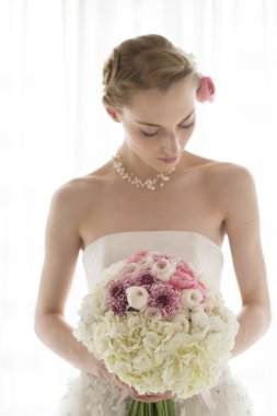 Gelin beyaz bir buket gül ve aşk çiçeği tutuyor.