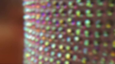 Bulanık video yavaş çekim. Karanlık ızgarada parıldayan renkli ışık noktalarını içeren soyut bir sahte arkaplan. Gökkuşağının yumuşak, bulanık renkleri rüya gibi bir festival yaratıyor.