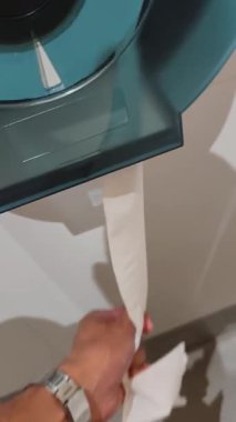 4K video kaydı. Bir insan modern bir banyodaki beyaz tuvalet kağıdını büyük, yarı şeffaf bir şeker kutusundan çıkarır.