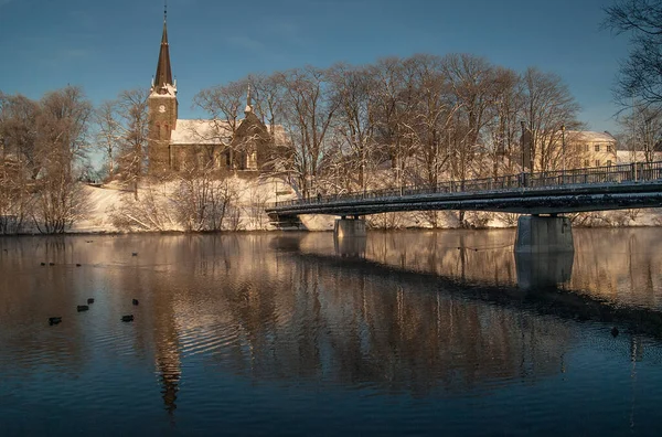 Ilen Kilisesi, Trondheim, Norveç. Güzel kış havası. Manzara ve karla kaplı kilise. Nidelven nehri üzerindeki köprü. Sudaki yansımalar. Mavi gökyüzü arkaplanı.