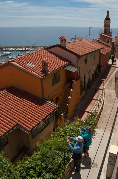 Eski şehrin çatıları, Menton, Fransa. İki turist selfie çekiyor. Arka planda Akdeniz.