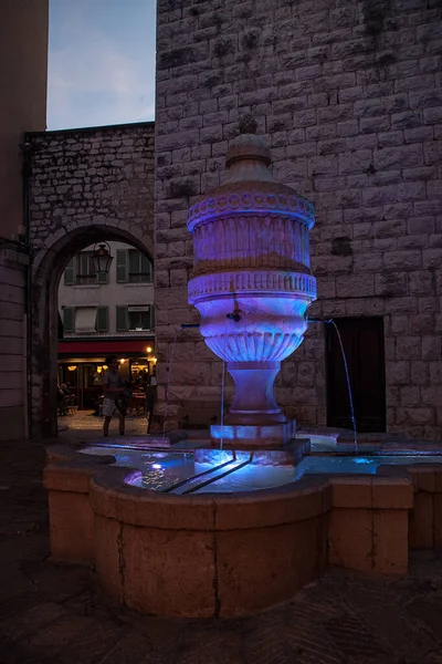 Fontaine De Payra, Vence, Fransa, tarihi bir anıt. Arka planda eski şehrin girişlerinden biri var. Güzel neon mavisi bir renk. Dikey fotoğraf.
