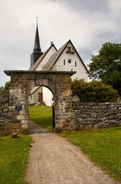 Tingvoll Church, Tingvoll, Norway. The 800 years old Romanesque style church is surrounded by a beautiful stone fence with a beautiful stone archway.