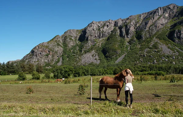 Girl with horse in green summer field