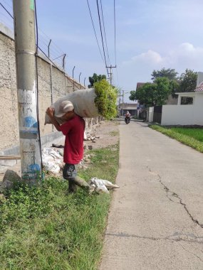 Cikancung, Batı Java, Endonezya - 14 Haziran 2021: Hasat edilmiş pirinci çuvalda taşıyan bir çiftçinin fotoğrafı
