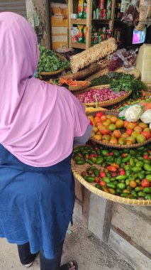 Cikancung , Indonesia - July 12, 2021 : Photo of a middle-aged woman in a hood shopping at the Cikancung market
