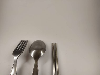 Beyaz arka planda izole edilmiş kaşık, çatal ve çubuk şeklinde üç çatal bıçak takımı.