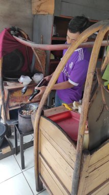 Bandung, Endonezya - 29 Temmuz 2021: Tipik bir Endonezya yemeği hazırlayan bir gıda satıcısının portresi, yani Tongseng, baharat açısından zengin bir çorbada pişirilmiş koyun eti..