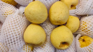 Photo of a pile of pears packed in nets and sold in supermarkets
