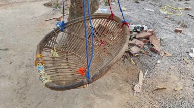 Bambu sandalyelerden ve ağaçtan sarkan plastik halatlardan oluşan bir salıncak.