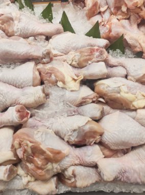 Buzdaki bir yığın tavuğun fotoğrafı. Taze kesilmiş tavuk etin tazeliğini korumak için bir dükkan vitrininde buzla sergilenir. Çiğ gıda malzemelerinin geçmişi